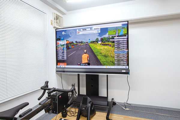 The Zwift motorcycle running display on a 77-inch large TV. 
